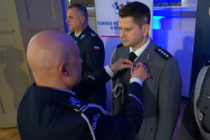 policjant przypina do munduru funkcjonariusza medal