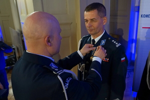 policjant przypina do munduru funkcjonariusza medal