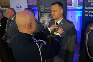 policjant przypina do munduru funkcjonariusza medal