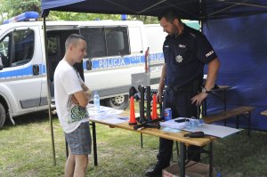 Policjant prezentuje sprzęt służbowy na festynie.