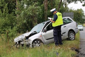 Policjant ruchu drogowego wykonuje oględziny pojazdu na miejscu wypadku drogowego w Piastoszynie.