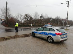 Policjant ruchu drogowego w sprawdzający prędkość pojazdów przy pomocy ręcznego miernika.