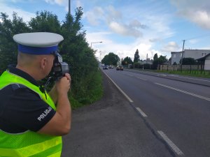 Policjant ruchu drogowego, kontrolujący laserowym miernikiem prędkość pojazdów.