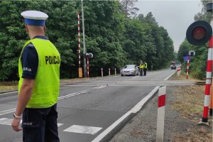 stojący policjant obserwuje ruch w rejonie przejazdu kolejowego