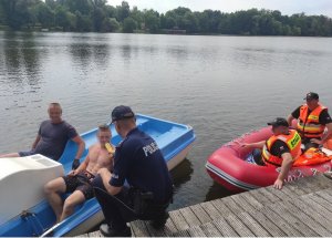 Funkcjonariusz policji wykonuje badanie stanu trzeźwości osób pływających na rowerze wodnym.