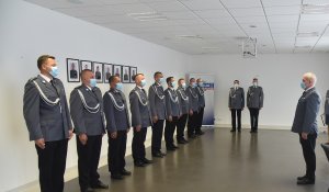 Stojący policjanci wysłuchują przemówienia komendanta