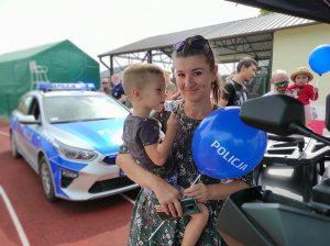 kobieta z dzieckiem trzyma balon z napisem policja