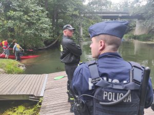 policjant i strażak obserwują płynących kajakarzy