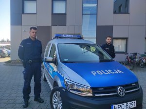 policjanci stoją przy radiowozie