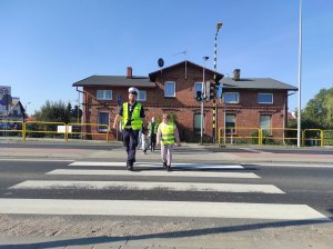 policjant przeprowadza dzieci przez przejście dla pieszych