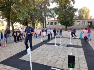 policjant pokazuje jak poruszać się bezpiecznie po drodze