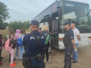 policjanci obserwują wsiadające dzieci do autokaru