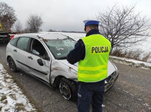 policjant wykonuje oględziny rozbitego auta