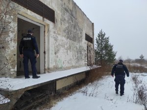 policjanci sprawdzają, czy w opuszczonym budynku nie ma osób bezdomnych