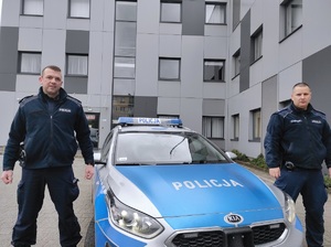 policjanci pozują do zdjęcia przy radiowozie