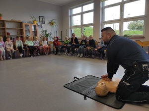 policjant prezentuje dzieciom jak prawidłowo udzielać pierwszej pomocy