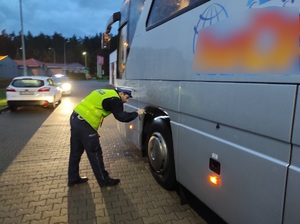 policjant sprawdza stan techniczny autokaru