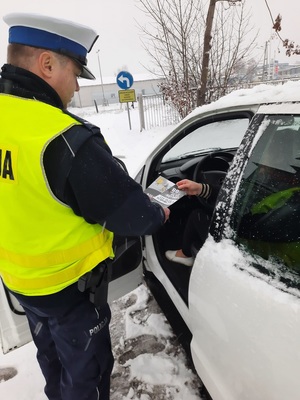 policjant daje kierowcy ulotki inforacyjne