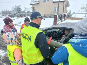 policjant i dzieci proszą kierowcę o bezpieczną jazdę