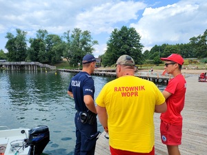 policjant i ratownicy wodni czuwają nad bezpieczeństwem osób wypoczywających nad wodą