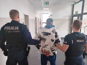 policjanci stoją z zatrzymanym mężczyzną