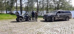 policjant i strażnik leśny stoją w kompleksie leśnym z pojazdem terenowym i Qadem
