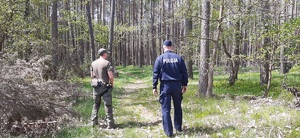 policjant i strażnik leśny idą w lesie
