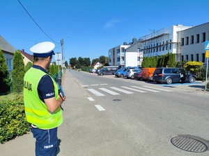 policjant kontroluje ruch drogowy na ulicy poza pojazdem oznakowanym