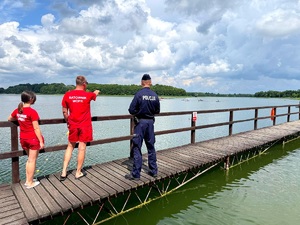 policjant i ratownicy wodni czuwają nad bezpieczeństwem osób wypoczywających nad akwenem