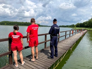 policjant i ratownicy wodni czuwają nad bezpieczeństwem osób wypoczywających nad akwenem