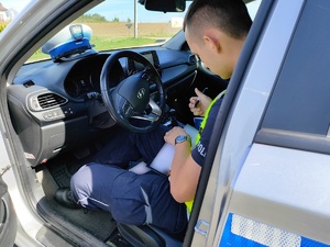 policjant sporządza dokumentacje w radiowozie - zdjęcie poglądowe