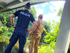 policjant i strażak obserwują wodę