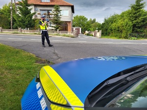 Radiowóz i policjant z urządzeniem pomiarowym (miernikiem prędkości)