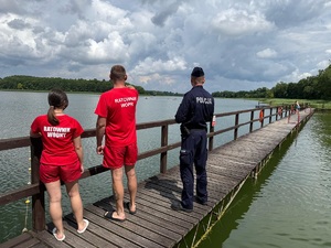 Kontrola akwenu, policjant wraz z ratownikami obserwują jezioro