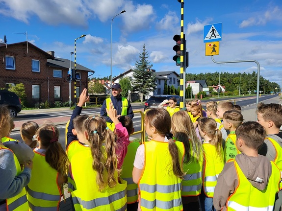 policjant omawia dzieciom zasady bezpieczeństwa na drodze