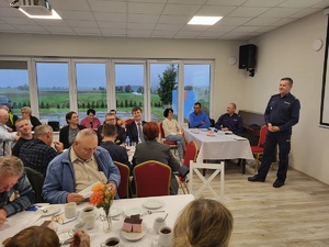 na zdjęciu widać policjanta i siedzących ludzi